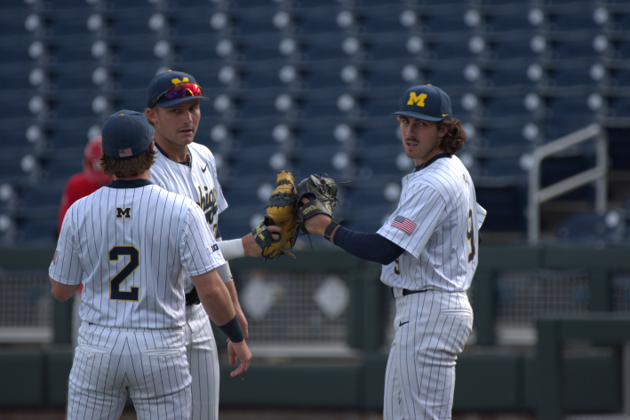 Michigan right-handed pitcher Cade Montgomery (right) taps gloves with his teammates before starting an inning against Rutgers in the 2026 Big Ten Baseball Tournament (Photo by Josh Nelson, Sox Machine)